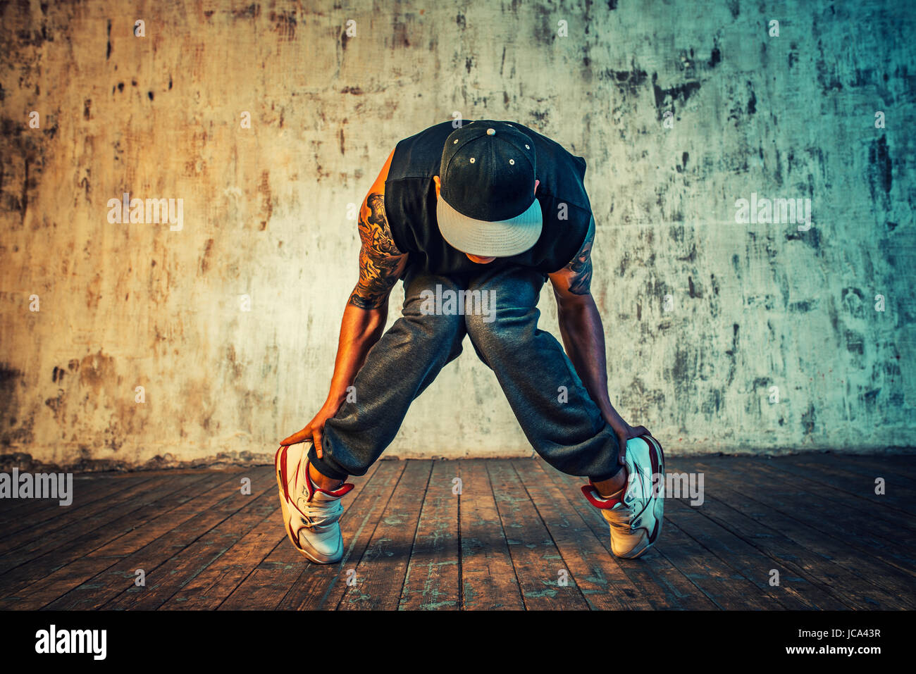 Junger Mann Breakdance auf Wand Hintergrund. Lebendigen Farben Effekt. Tattoo auf den Körper. Stockfoto
