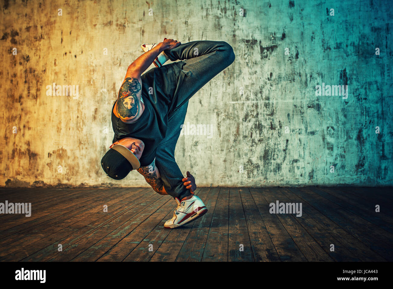 Junger Mann Breakdance und stehen auf einem Bein auf Wand Hintergrund. Lebendigen Farben Effekt. Tattoo auf den Körper. Stockfoto