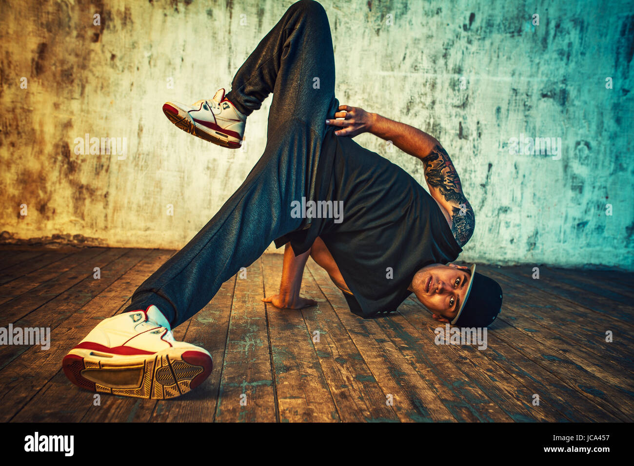 Junger Mann Breakdance auf Wand Hintergrund. Lebendigen Farben Effekt. Tattoo auf den Körper. Stockfoto