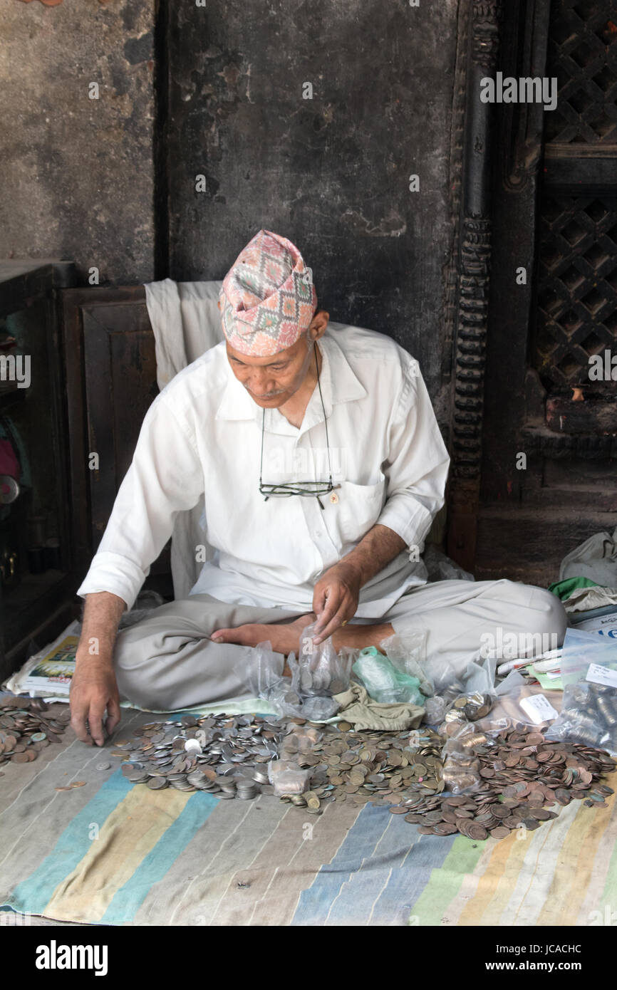 Mann in Newari Kleid counting-Münzen in einer Arkade auf Nepal Kathmandu Durbar Square Stockfoto