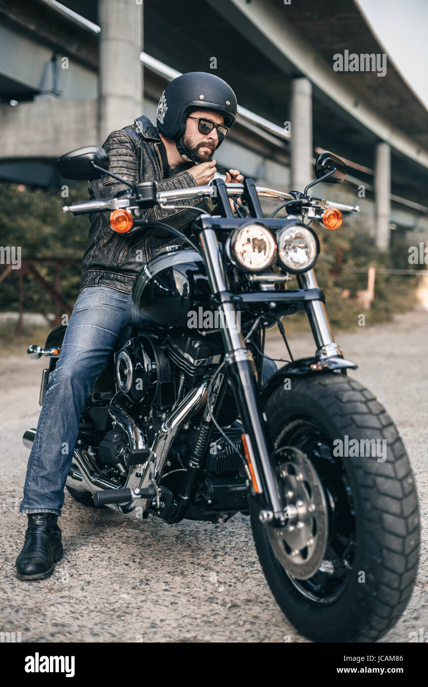 Brutale Jüngling in einer schwarzen Jacke und Gläser auf Motorrad Stockfoto