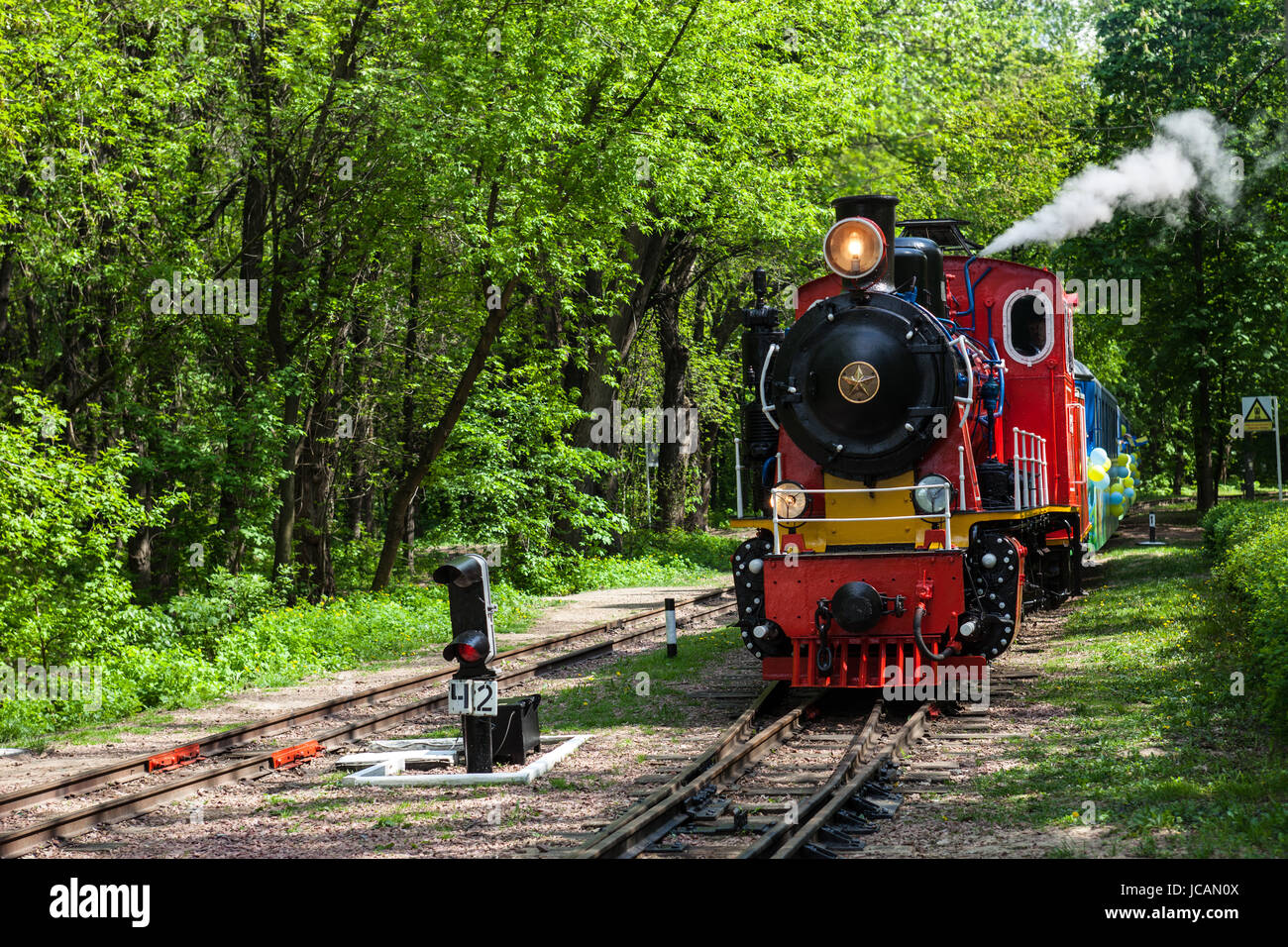 Dampf-Lokomotive durch den Park gehen und Abblasen des Dampfes aus der Pfeife Stockfoto