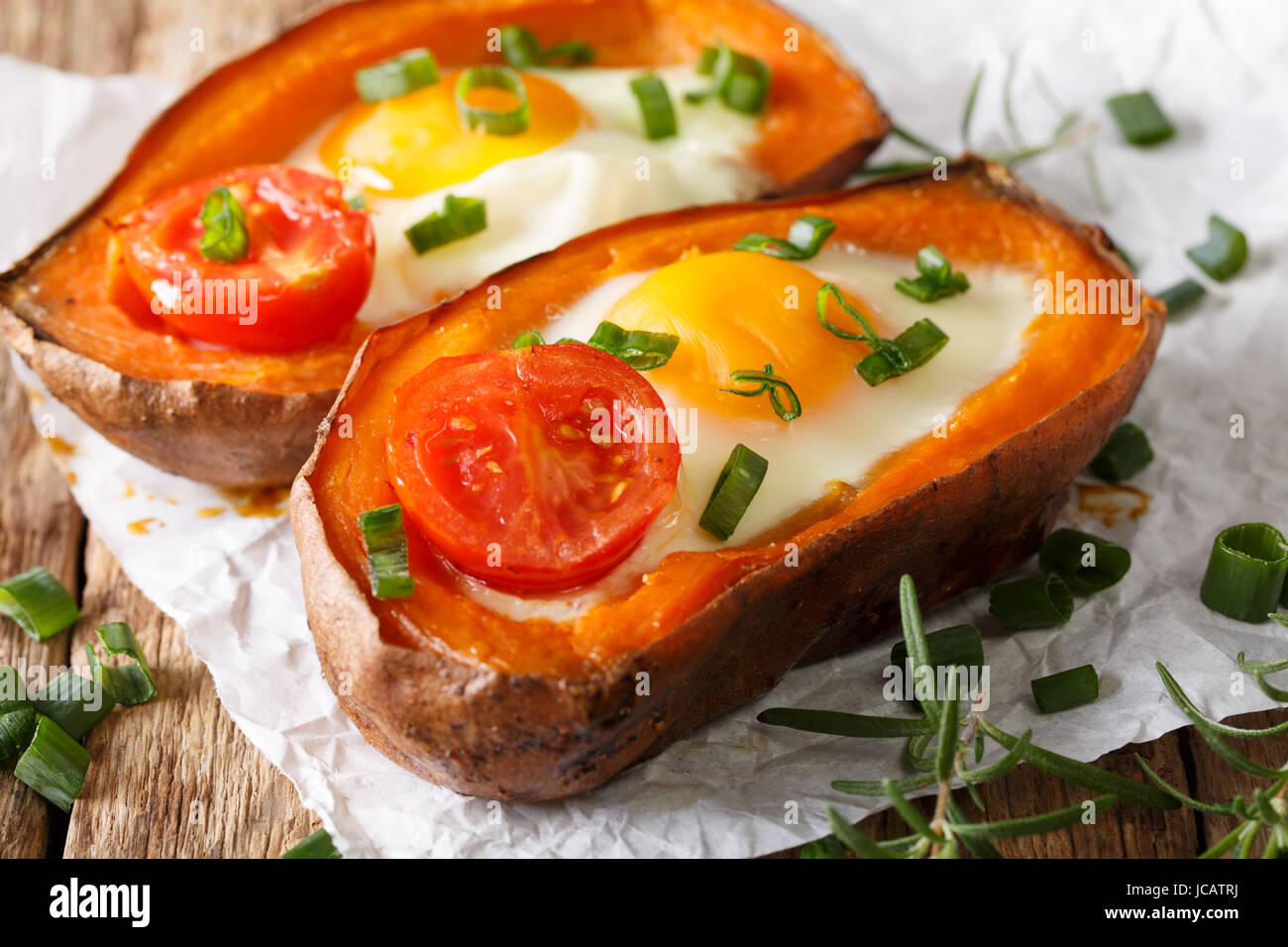 gesunde gebackene Süßkartoffel mit Spiegelei und Tomaten-close-up auf dem Tisch. Horizontale Stockfoto