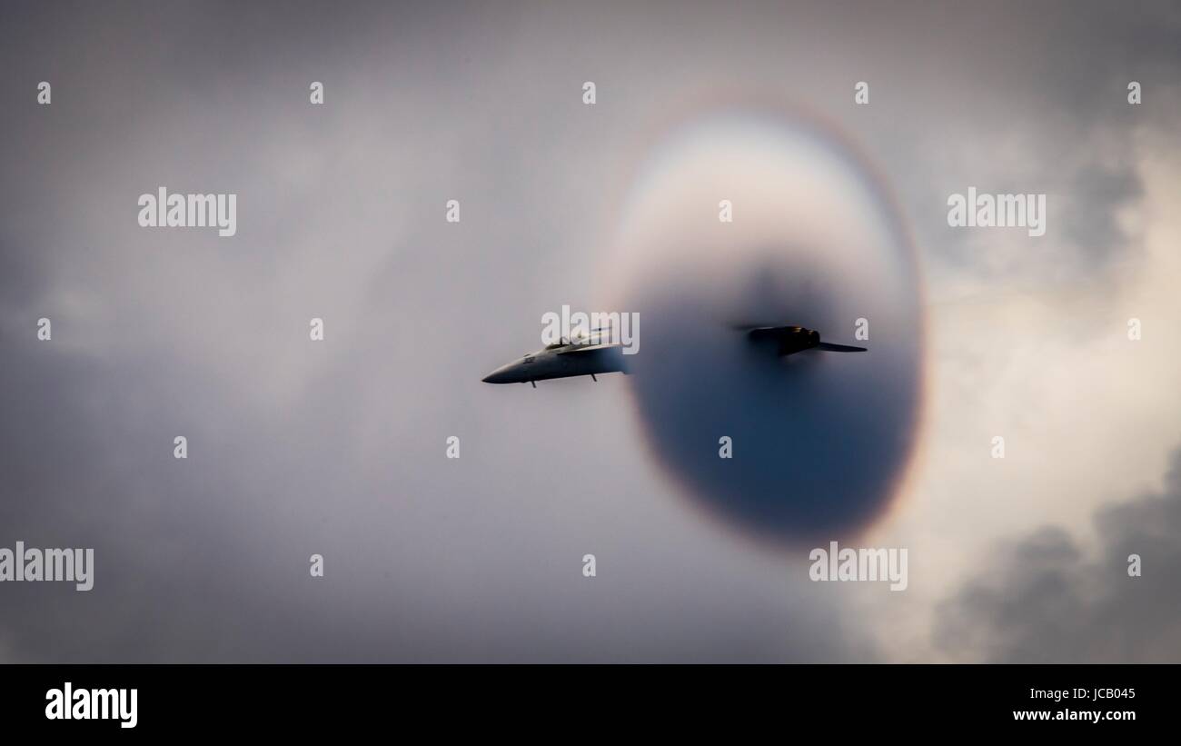 Ein Kampfflugzeug der US Navy F/A-18E Super Hornet der Strike Fighter Squadron 192 goldenen Drachen schafft einen Dampf-Kegel, wie es die Schallmauer während des Betriebs über die Flugzeugträger der Nimitz-Klasse USS Carl Vinson 12. Juni 2017 im Pazifischen Ozean bricht. Stockfoto