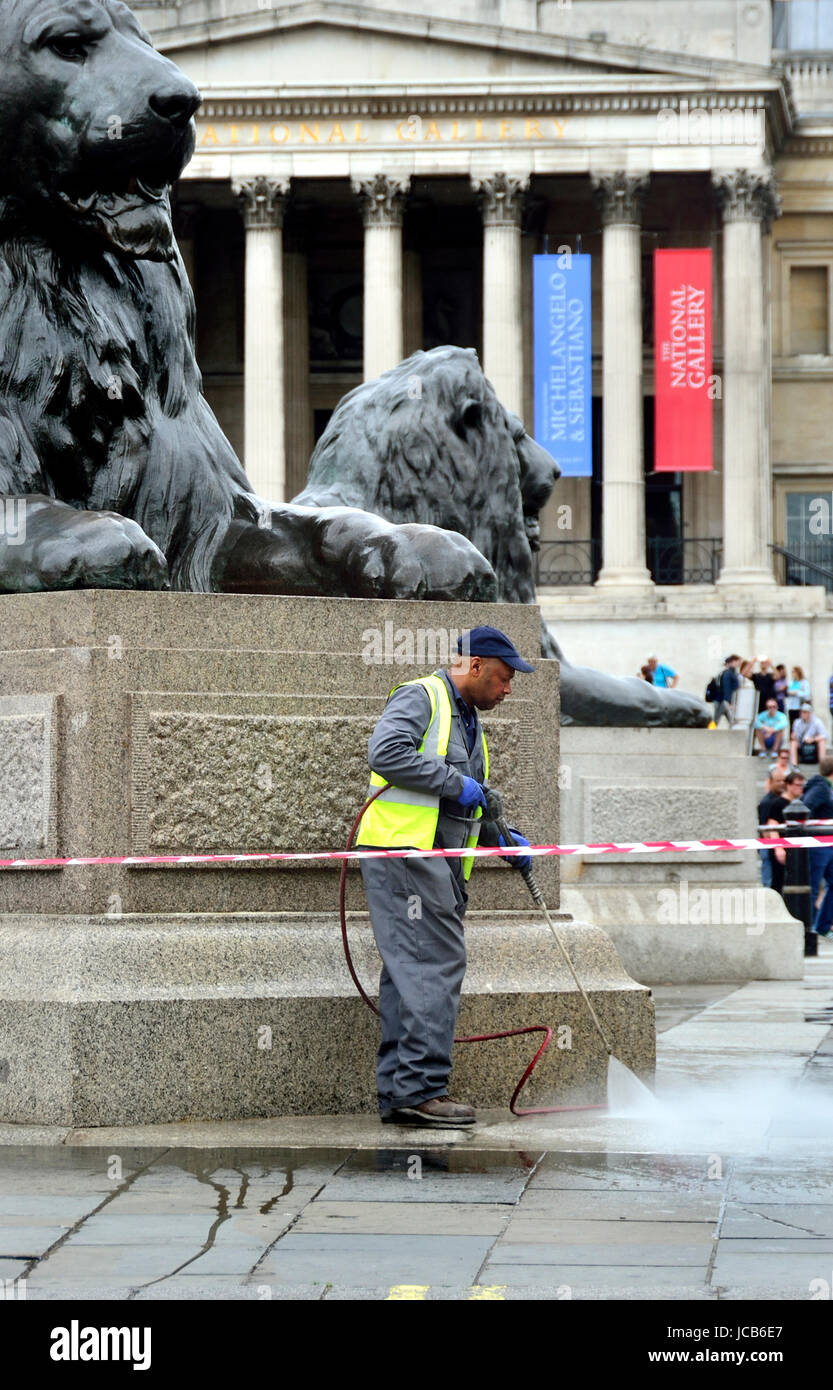 London, England, Vereinigtes Königreich. Auftragnehmer, die Reinigung die Löwen auf dem Trafalgar Square mit einem Schlauch / Druck Waschmaschine Stockfoto
