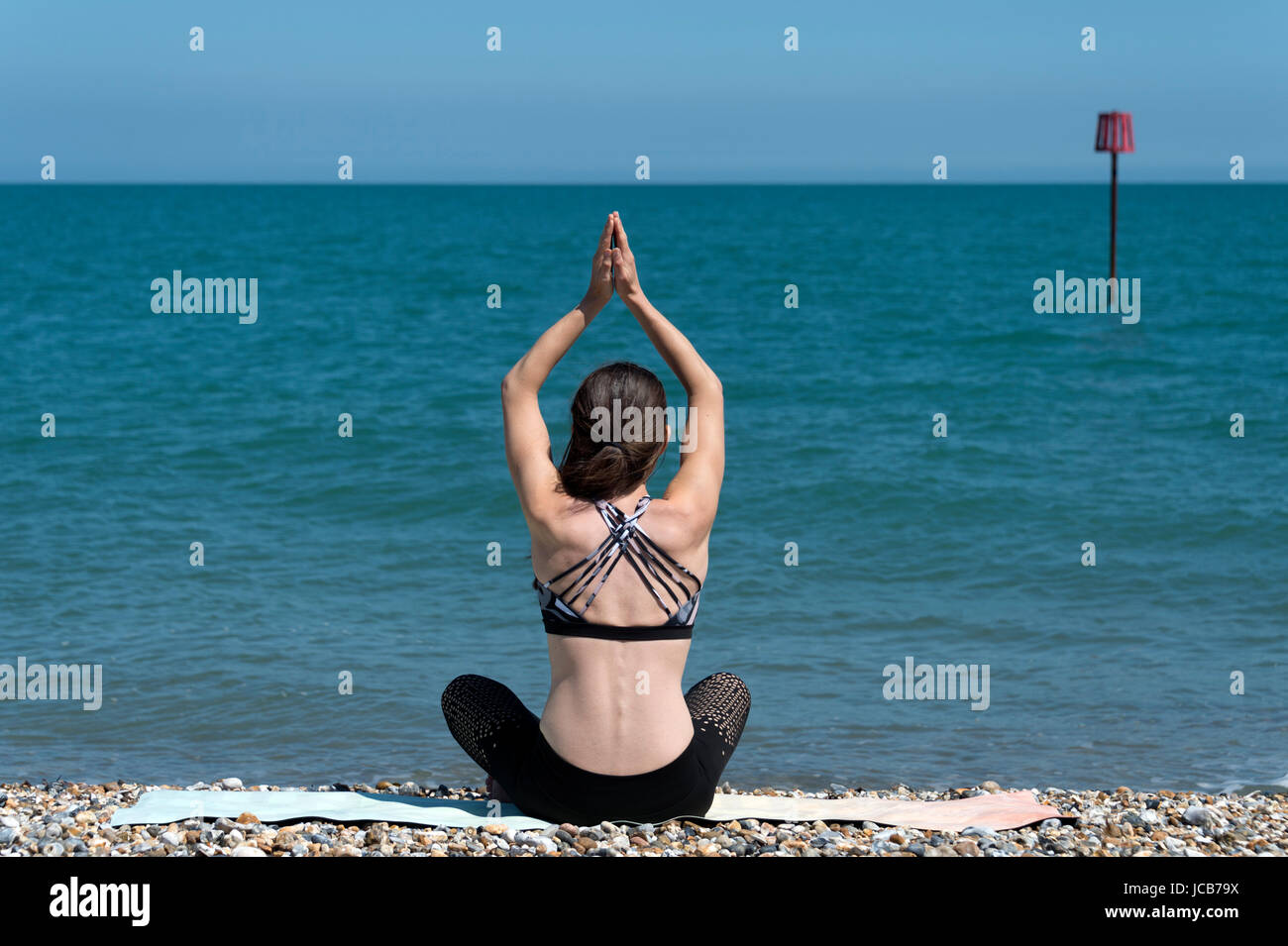 Frau beim Yoga am Strand, Baumpose Stockfoto