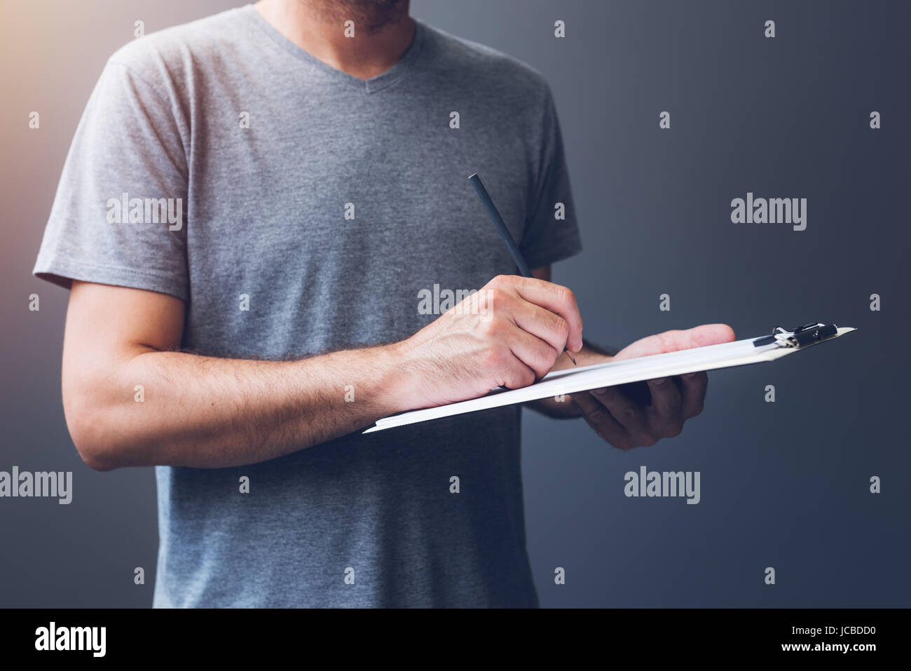 Lässige Männchen Schreiben von Notizen auf Papier Notizblock, unkenntlich Mann im grauen T-shirt mit Bleistift Stockfoto