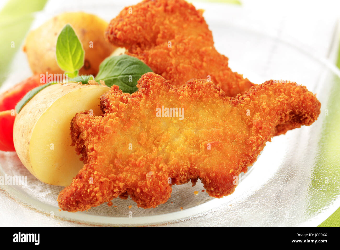 Fried-Dinosaurier-förmigen Fisch-Nuggets mit neuen Kartoffeln Stockfoto