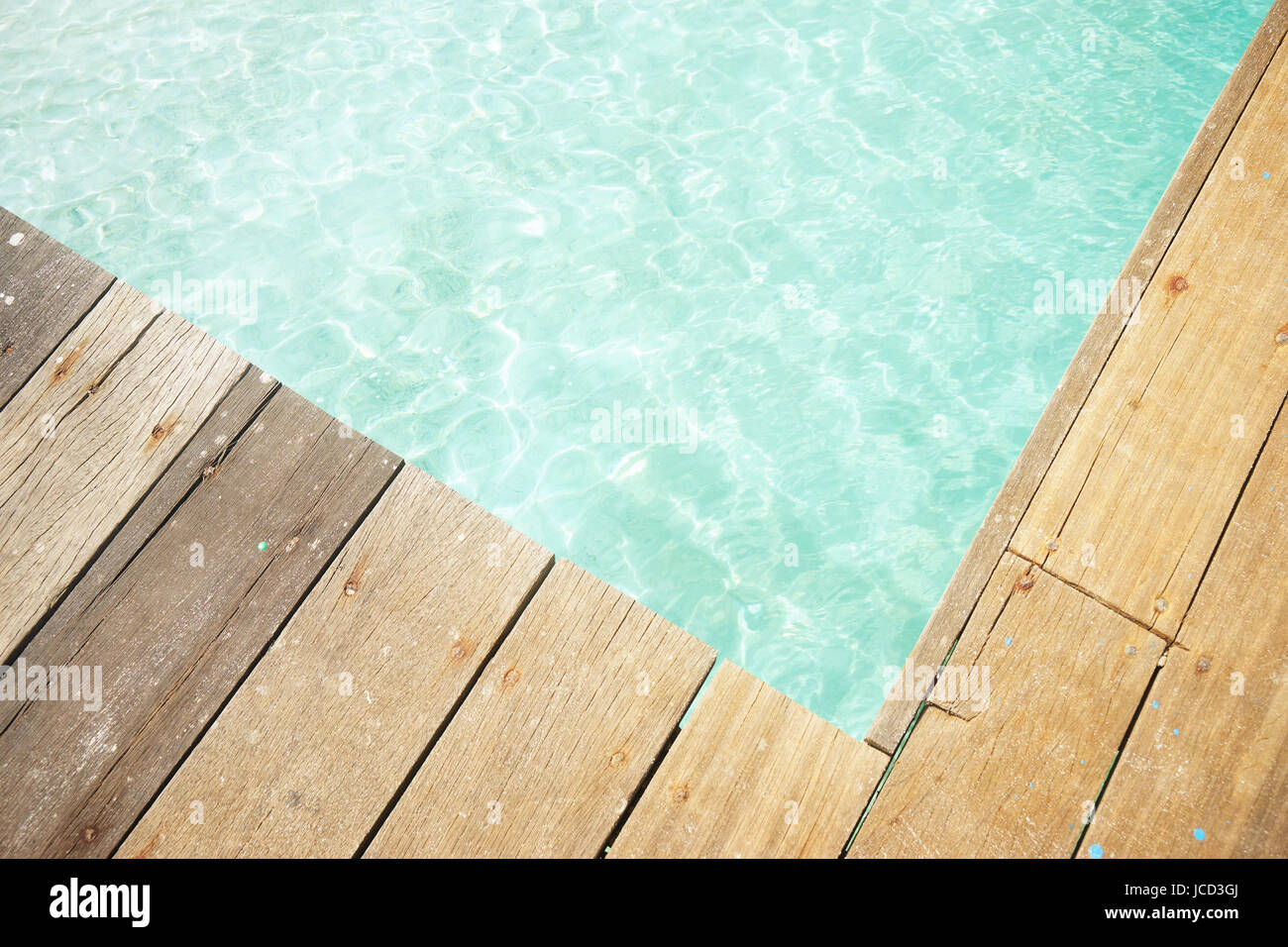 Holzsteg mit kristallklaren und türkisfarbenen Meerwasser des tropischen Meeres hautnah. Obere Winkel Ansicht. RAWA-Insel, Malaysia. Stockfoto