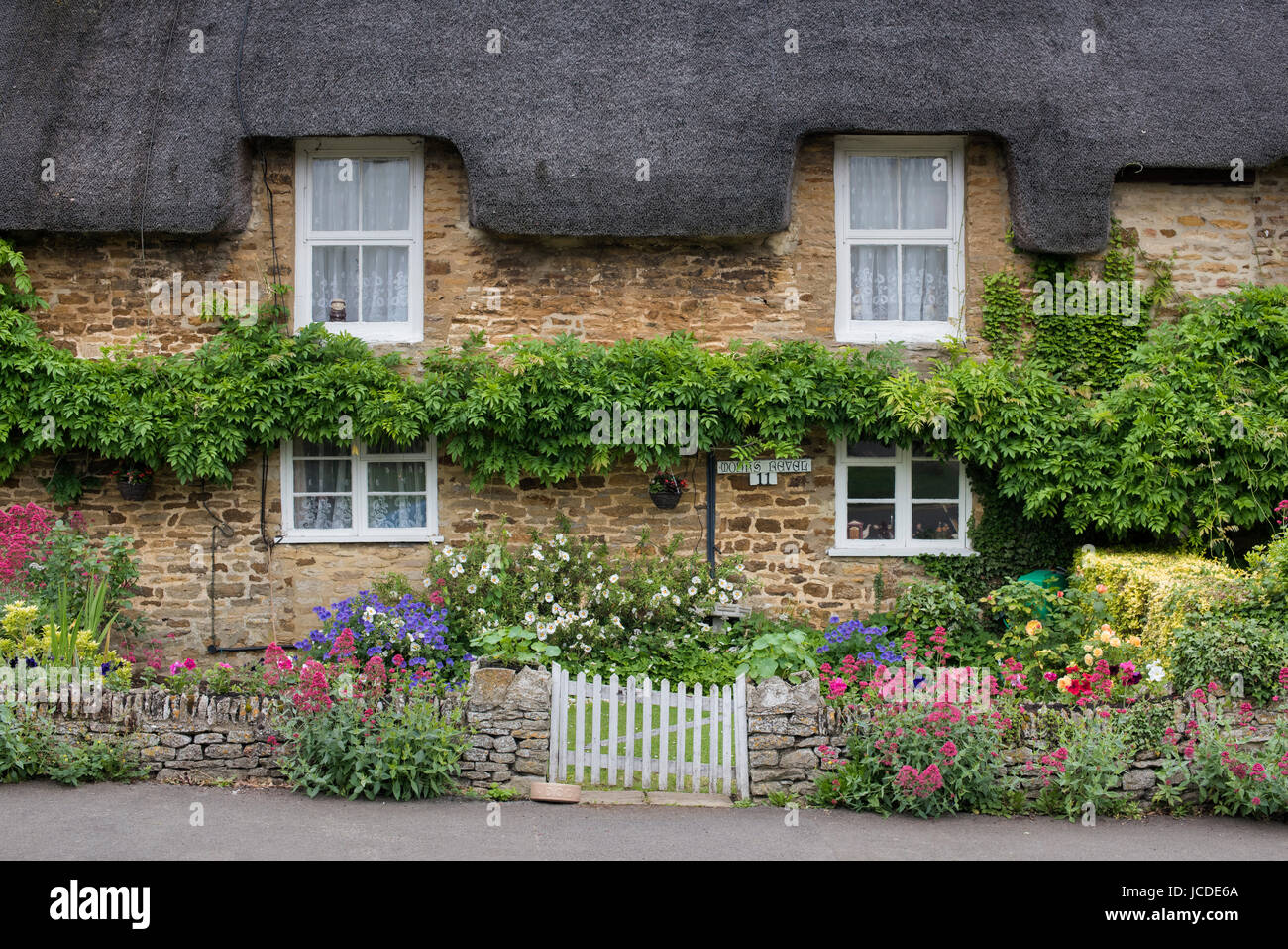 Steinerne Reetdachhaus und floralen Vorgarten im Frühjahr. Des Königs Sutton, Northamptonshire, UK Stockfoto