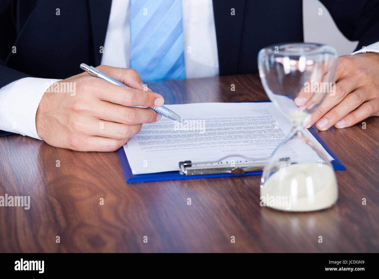 Nahaufnahme der Geschäftsmann Formular mit Sanduhr auf Schreibtisch Stockfoto