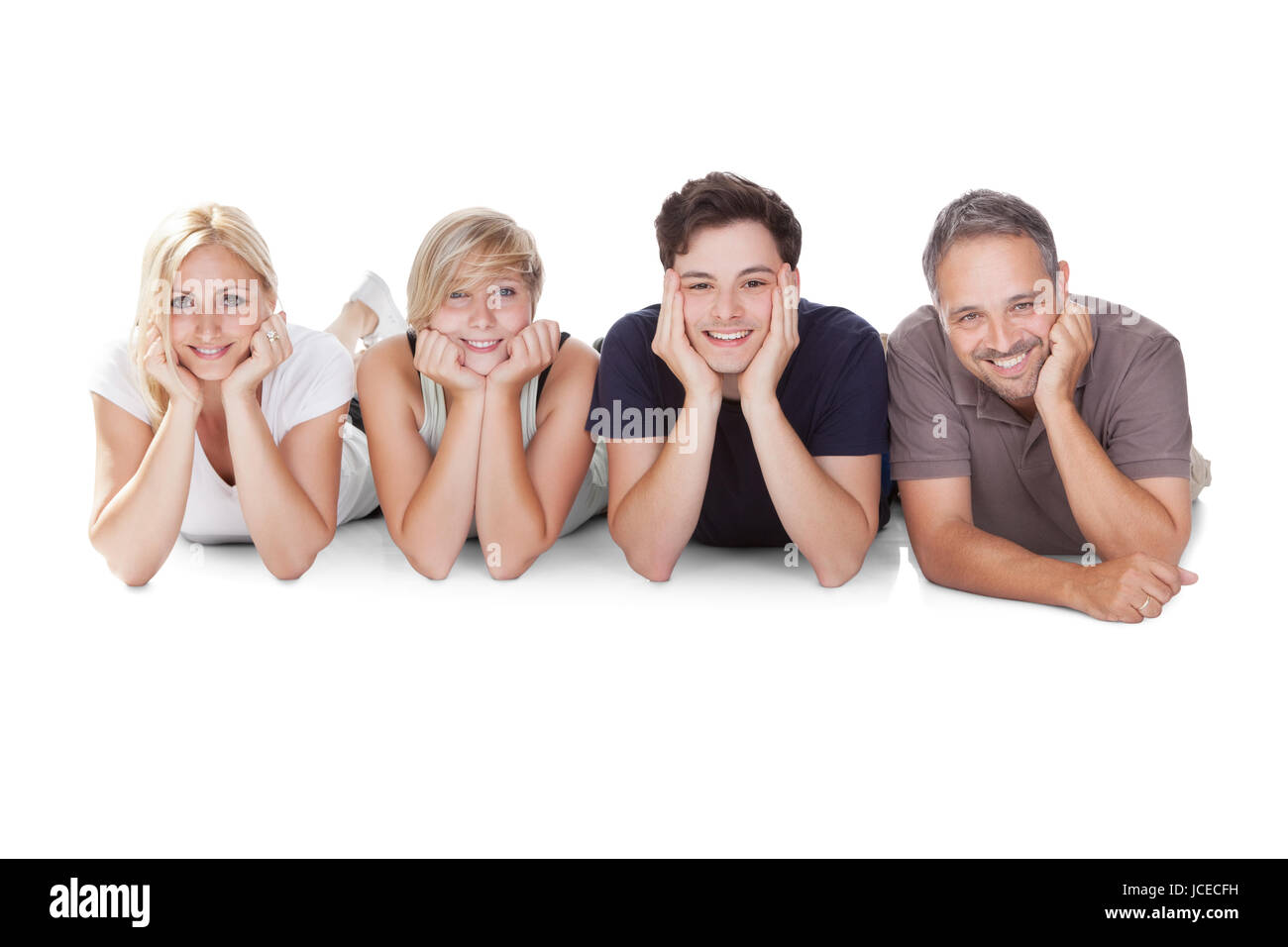 Glückliche freundliche Familie mit Teenager-Sohn und Tochter liegen hintereinander auf dem Boden auf dem Bauch entspannen, ruhen auf ihren Ellenbogen Stockfoto