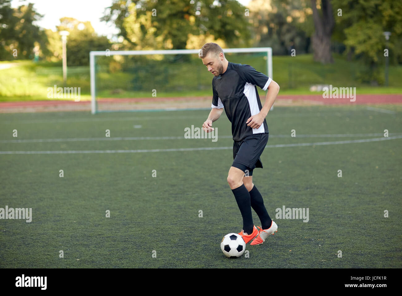 Fußballspieler mit Ball auf Fußballplatz spielen Stockfoto
