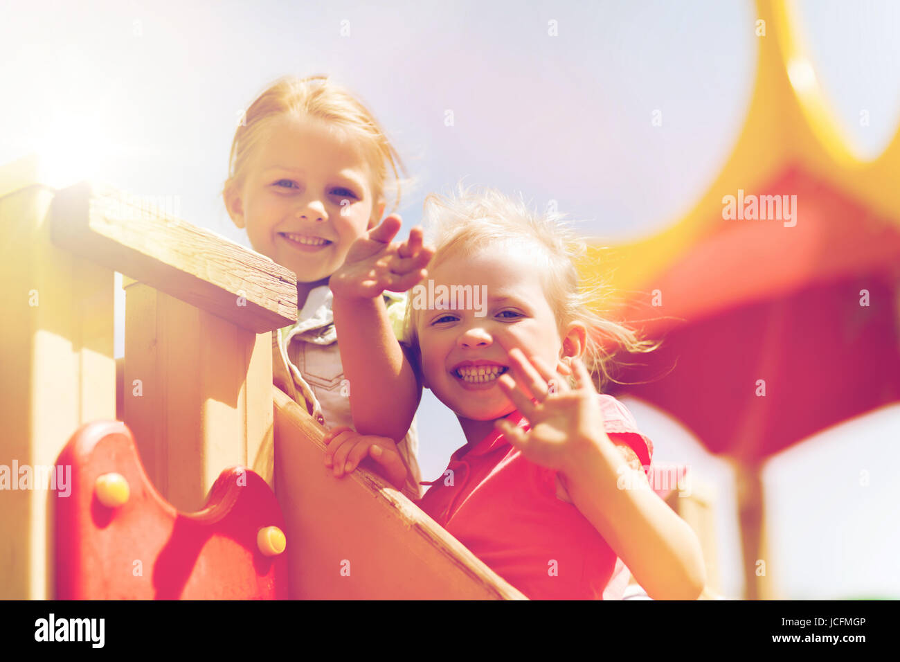 glückliche Mädchen winken Hände auf Kinderspielplatz Stockfoto