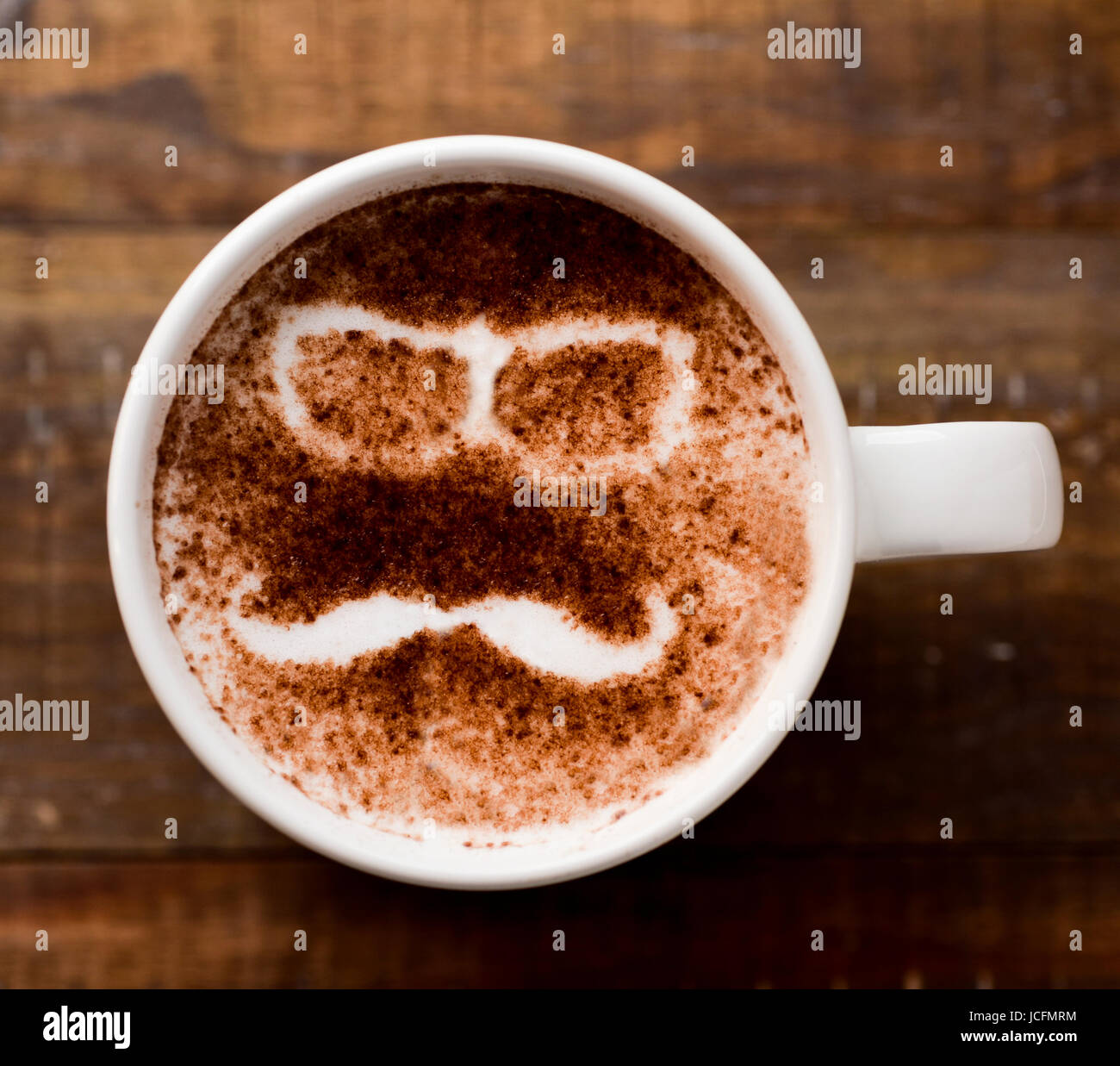 Nahaufnahme von einer Tasse Cappuccino mit ein paar Brillen und einen Schnurrbart, gezeichnet mit Kakaopulver auf den Schaum Stockfoto