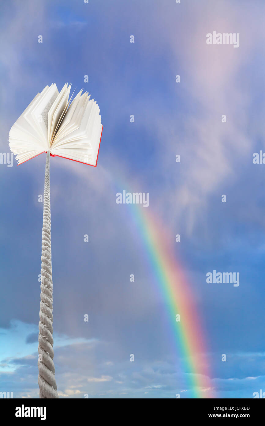 Buch, gebunden an Schnur schwingt sich in blauer Himmel mit Regenbogen Stockfoto