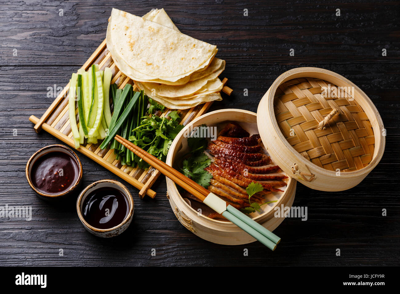 PekingEnte in Bambus Dampfgarer serviert mit frischen Gurken, Frühlingszwiebeln, Koriander und