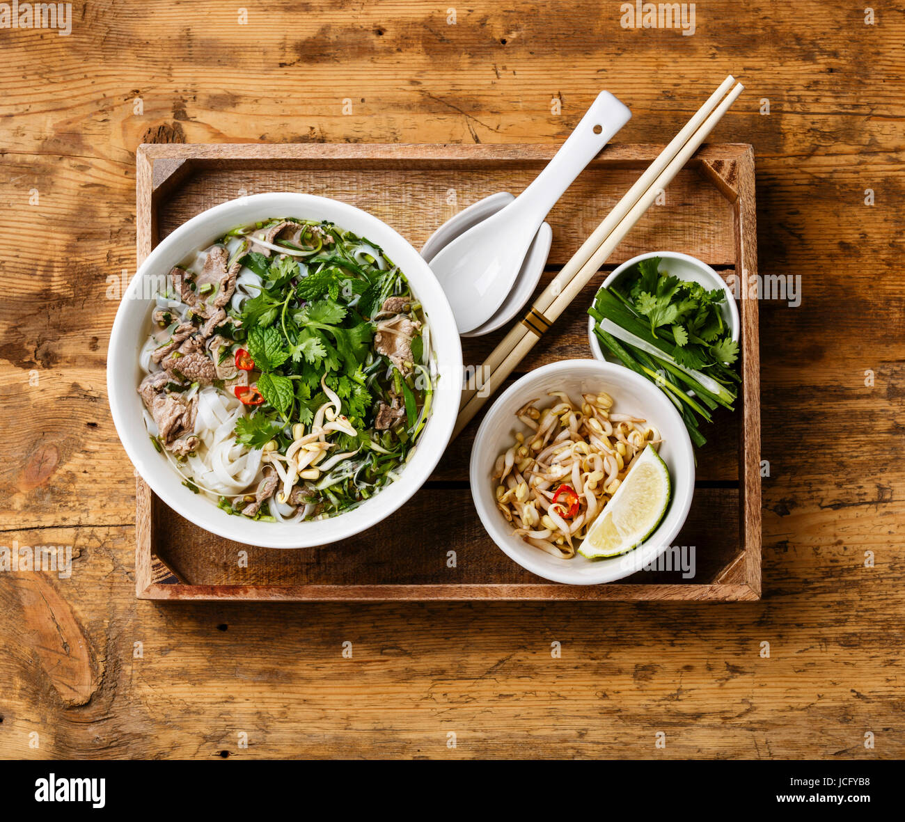 Pho Bo-vietnamesische Suppe mit Rindfleisch in Holztablett auf hölzernen Hintergrund Stockfoto