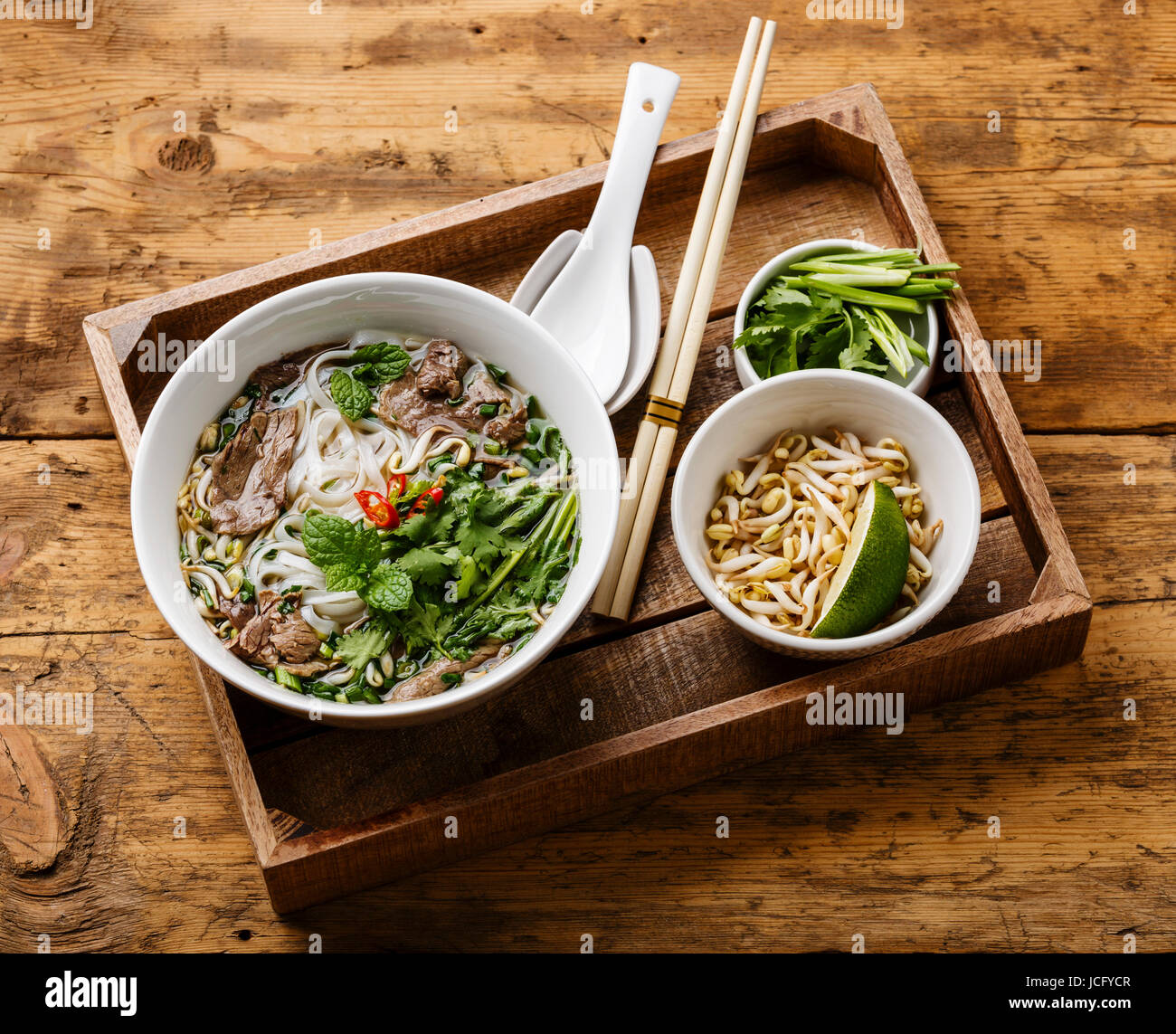 Pho Bo-vietnamesische Suppe mit Rindfleisch und Sojabohnen Keimlinge in Holztablett auf hölzernen Hintergrund Stockfoto