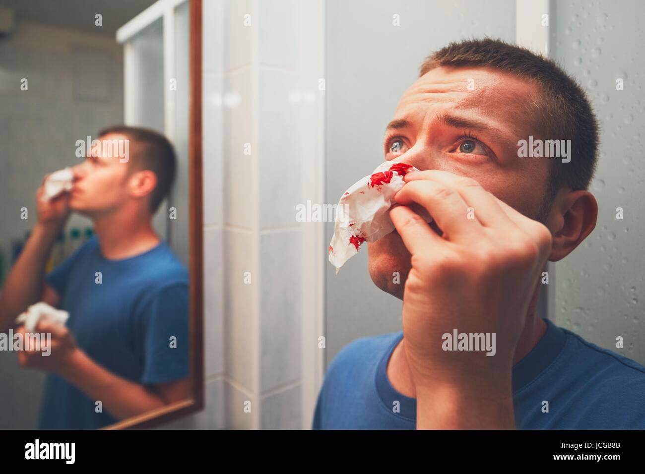 Mann mit Nasenbluten im Badezimmer. Für Themen wie Krankheit, Unfall oder Gewalt. Stockfoto