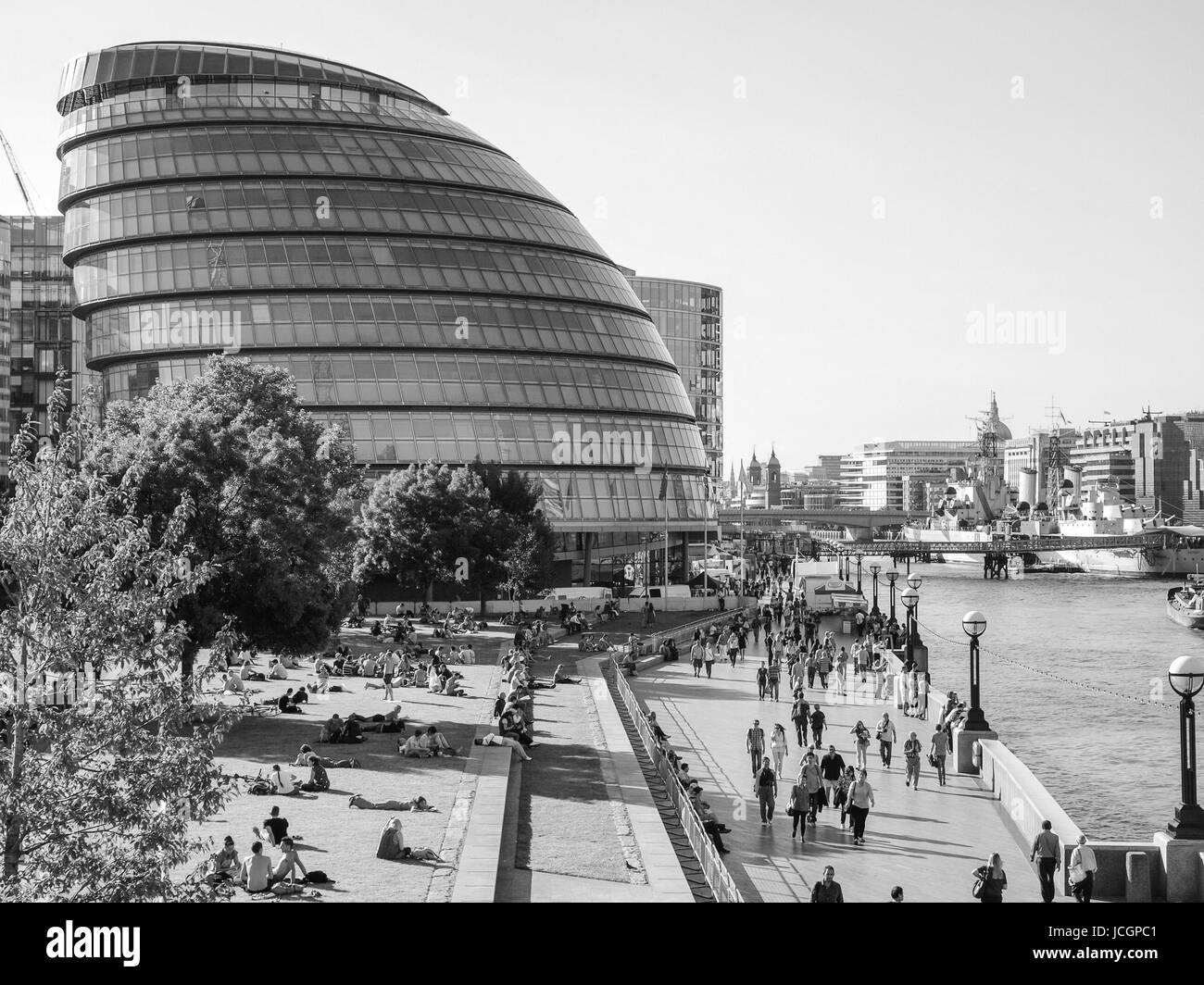 LONDON, ENGLAND, UK - 7. September 2012: Leute zum Sonnenbaden auf der Wiese vor dem größeren Londoner Behörde Rathaus aufbauend auf Themse im Jahr 2002 von Lord Norman Foster entworfen Stockfoto