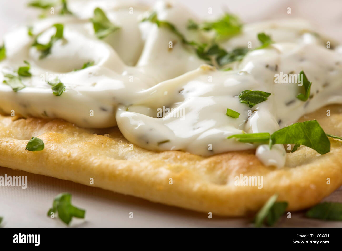 Nahaufnahme von einem dünne knusprige Cracker mit Frischkäse und Petersilie Stockfoto