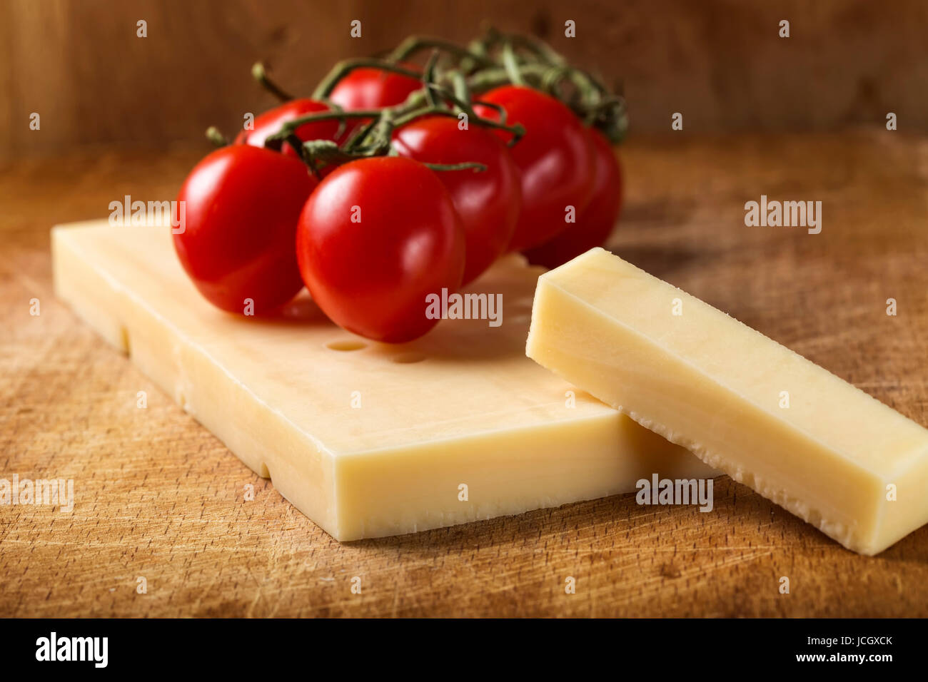 Nahaufnahme von Emmentaler Käse mit Cherry-Tomaten auf Holzbrett Stockfoto