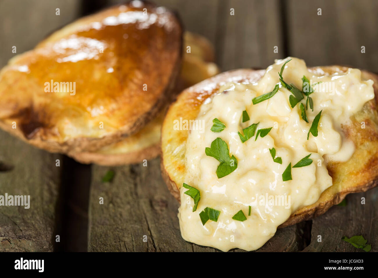 Nahaufnahme von gebackene Kartoffeln mit Knoblauch-Sauce über rustikale Holz Hintergrund Stockfoto