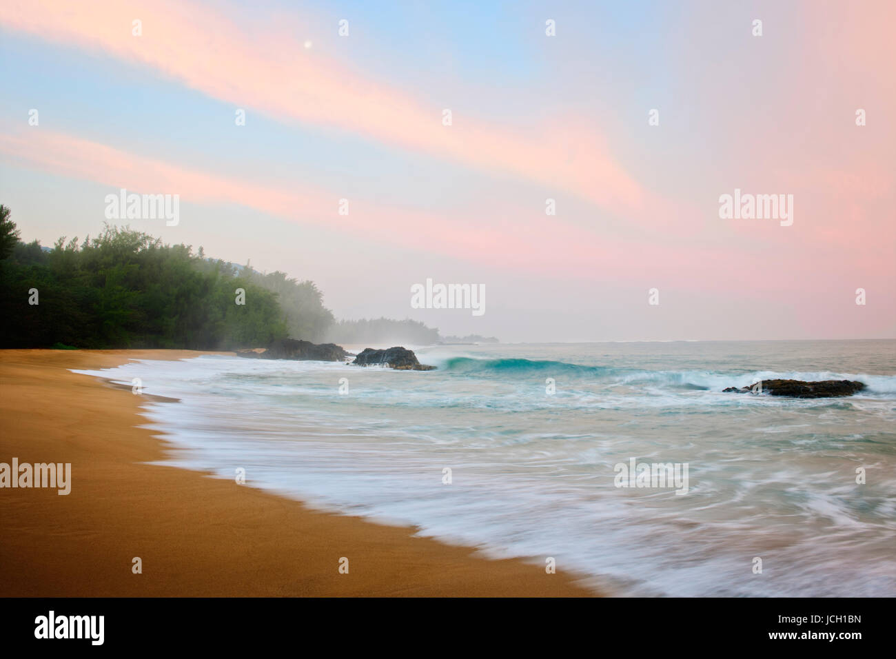 Mond setzt bei Sonnenaufgang entlang des nördlichen Ufers am Lumahai Beach auf Hawaii Insel Kauai. Stockfoto