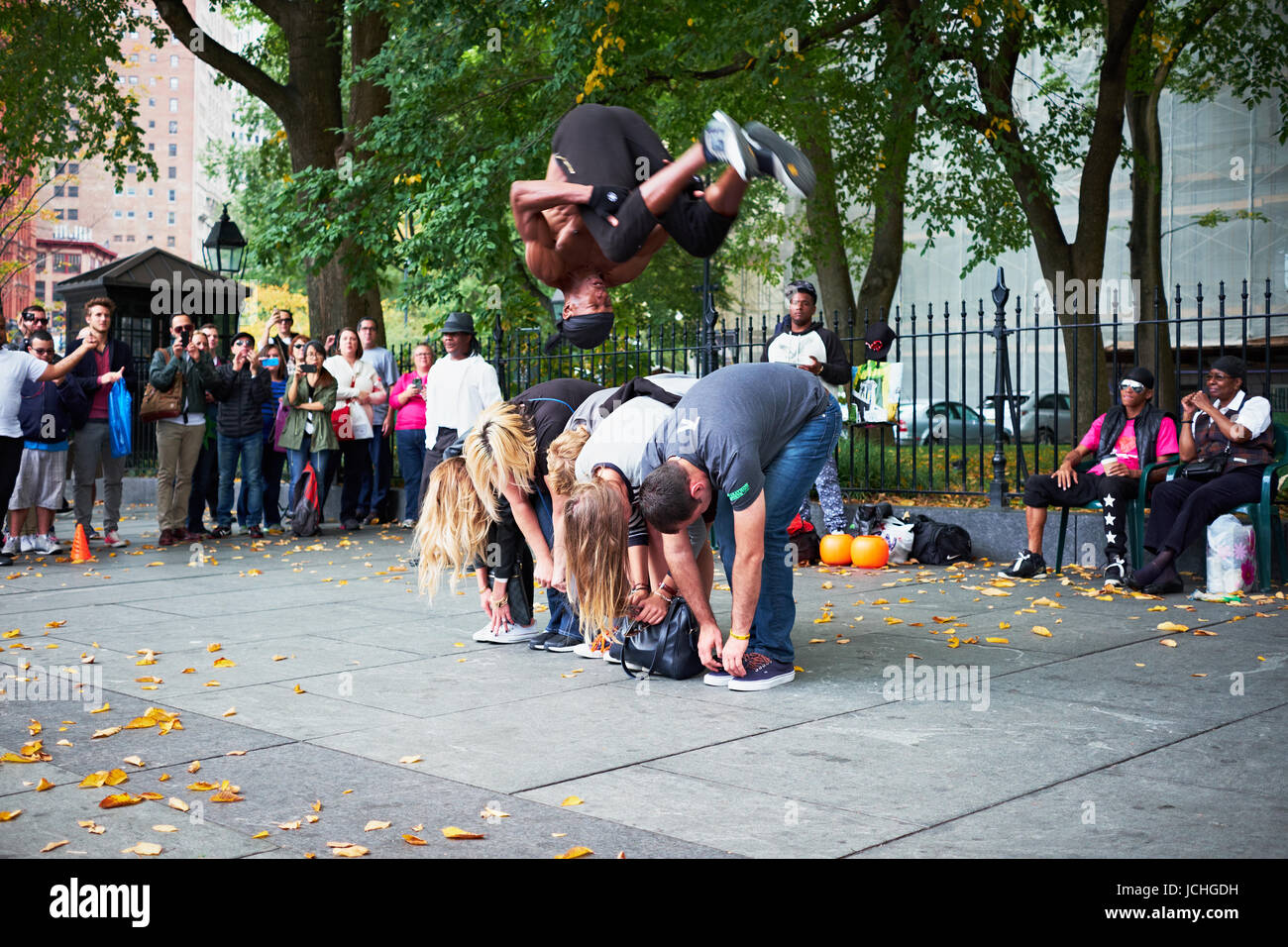 NEW YORK CITY - 18. Oktober 2014: ein Mann aus einer Performance-Gruppe macht einen Salto über eine Reihe von Touristen auf der Straße in Lower Manhattan Stockfoto