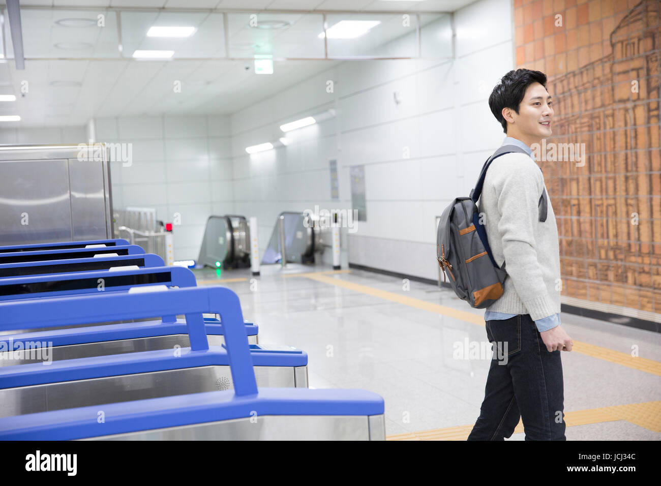 Junger lächelnder Mann zu Fuß in der u-Bahnstation Stockfoto