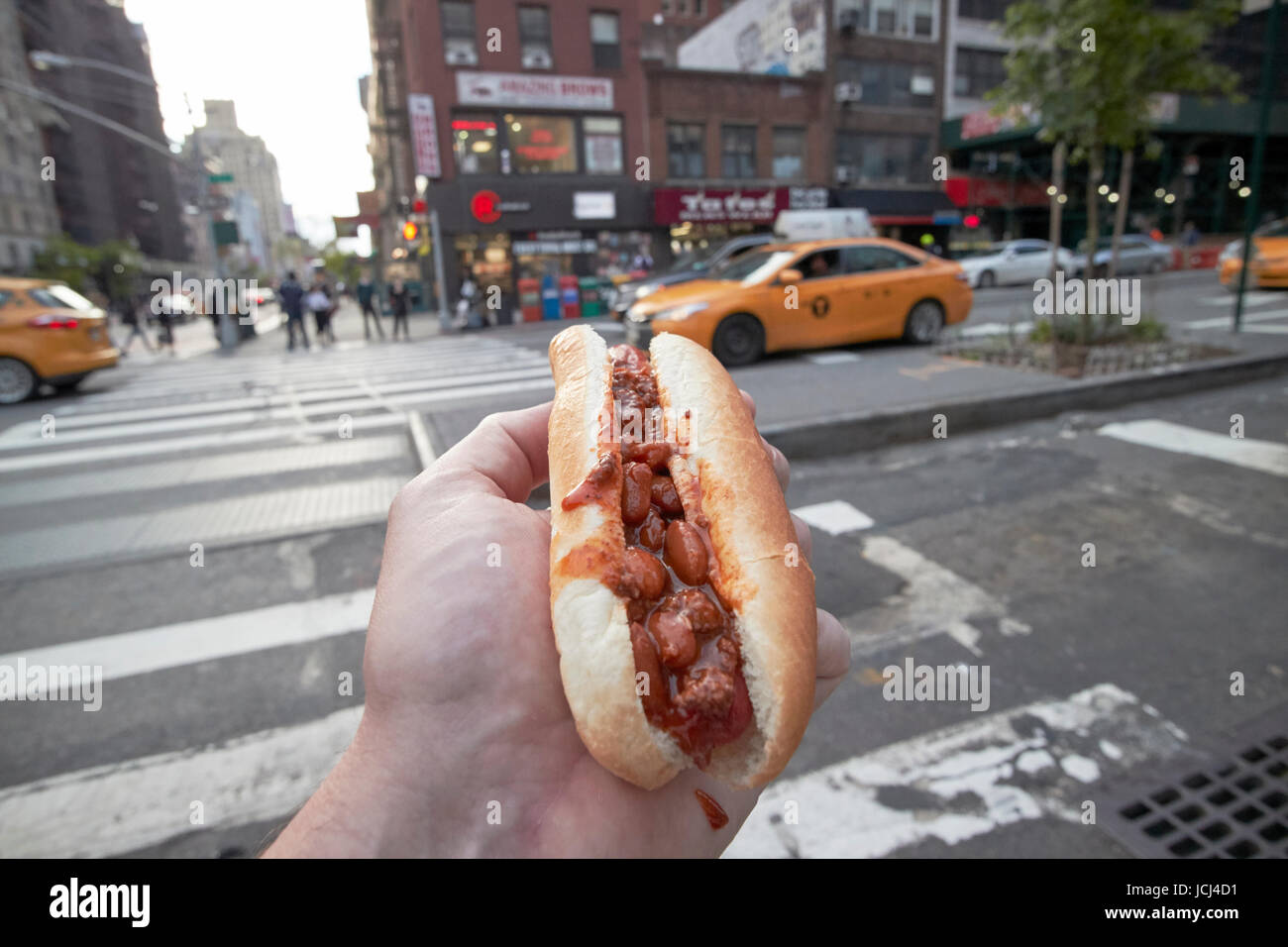 Mann mit Chili Hot Dog Essen in New York City, USA Stockfoto