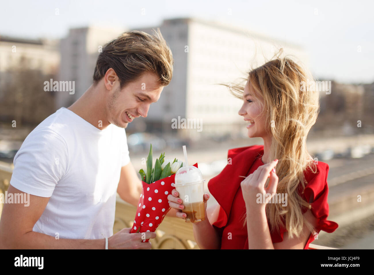 Junger Mann Frau im roten Kleid verleihen Strauß am ersten Tag Stockfoto