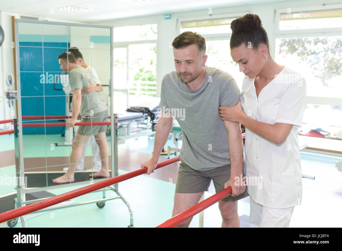 Mann auf Laufband mit Therapeuten hocken im Fitness-studio Stockfoto