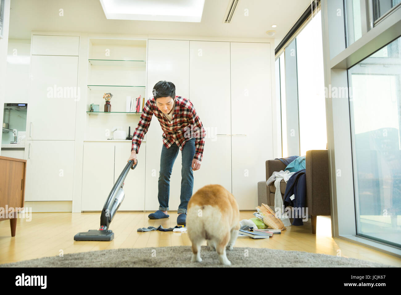 Junge Bachelor mit einem Haustier Hund sein Haus Reinigung Stockfoto