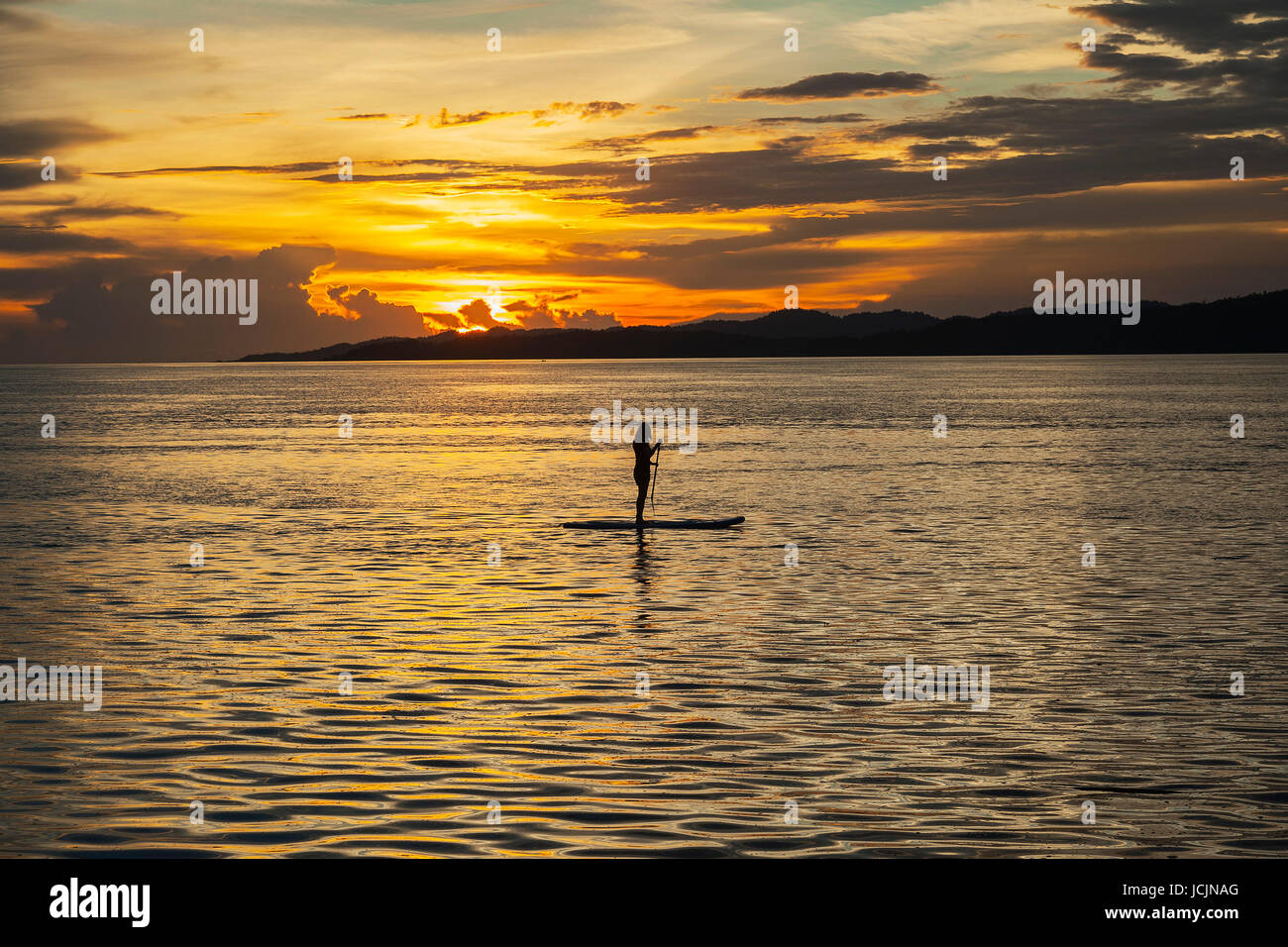 Frau auf standup Paddle Board im Meer bei Sonnenuntergang, Raja Ampat, Kri-Insel, Dampier-Straße, Western-Neu-Guinea, Indonesien Stockfoto