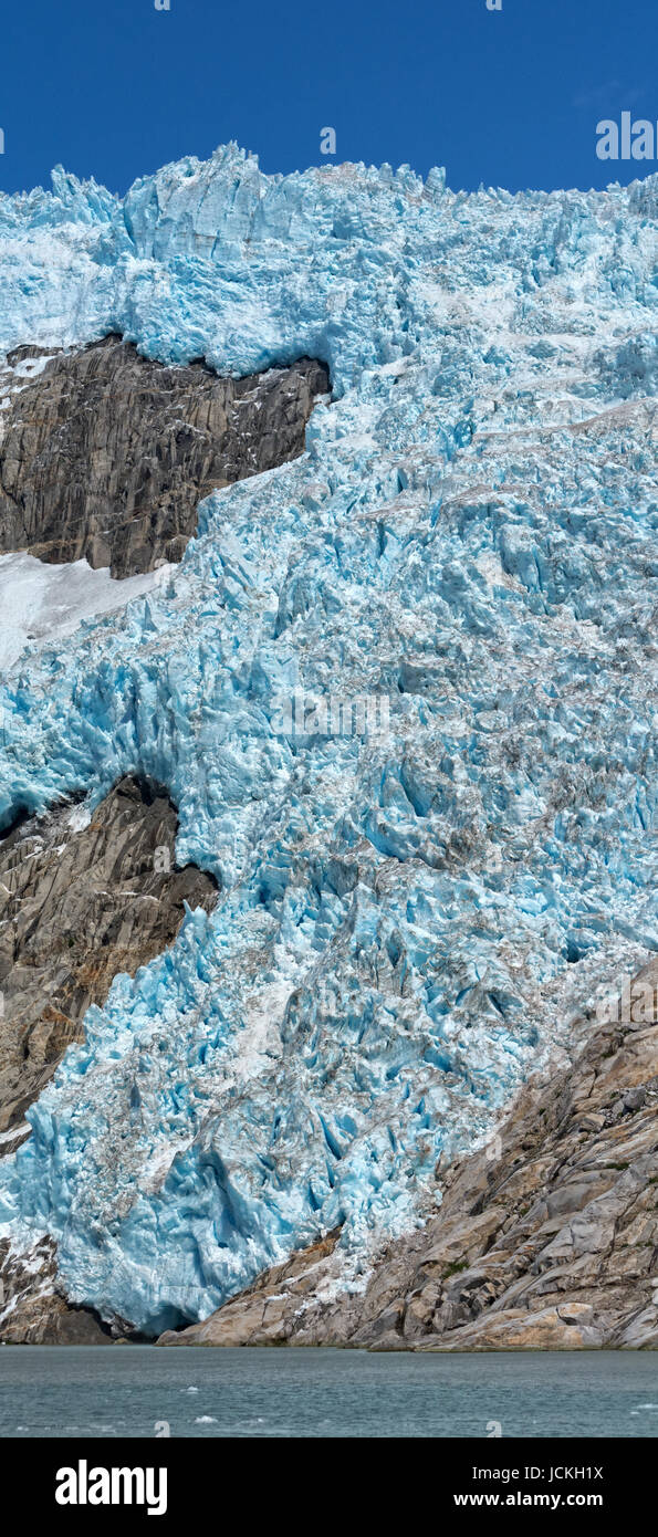 Eine steile Felswand herunterdrücken, erreicht blau weiße Gletscher das Meer. Stockfoto