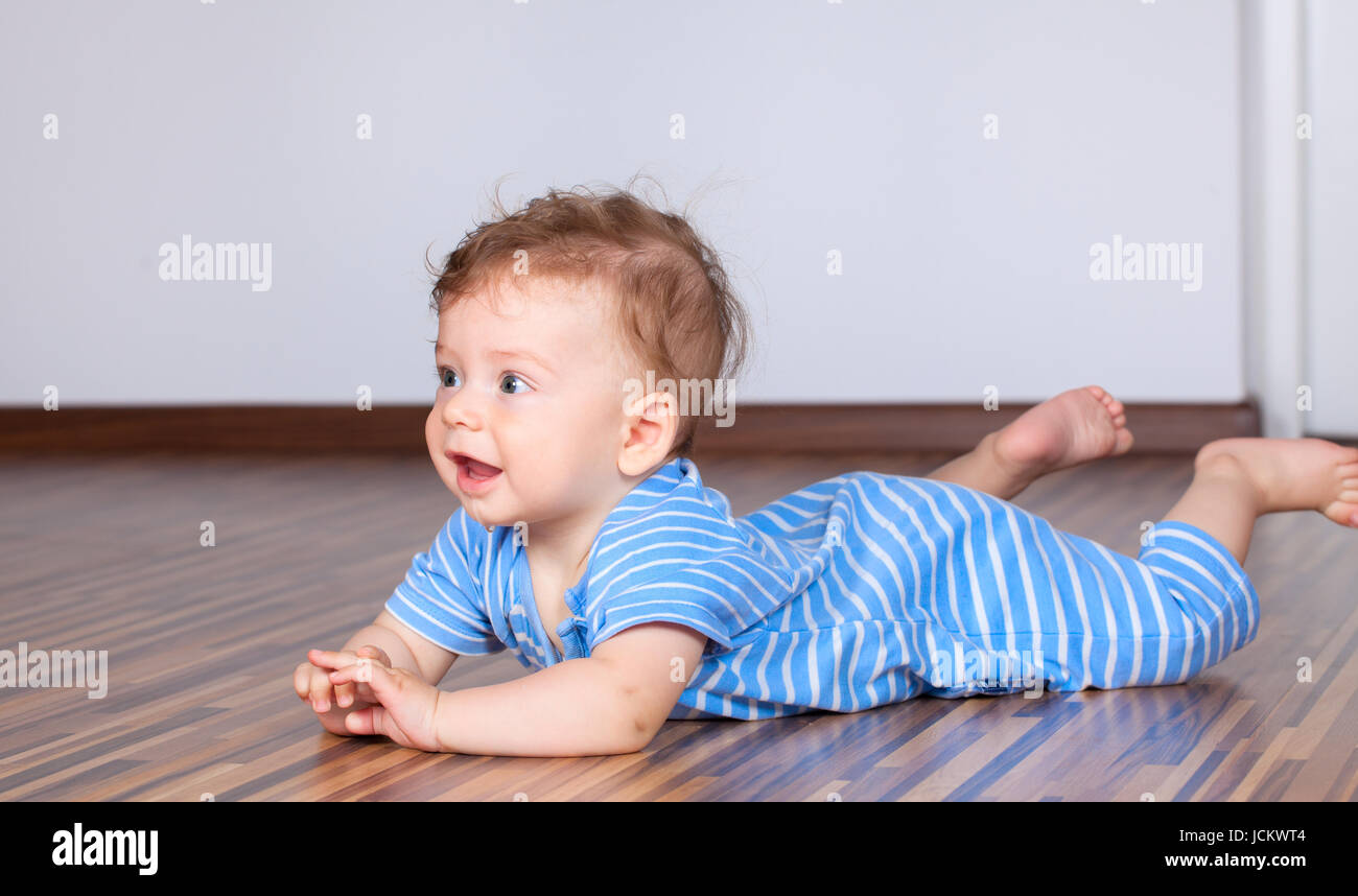 Porträt eines glückliche 6 Monate alten Baby jungen kriechen auf Holzboden zu Hause. Stockfoto