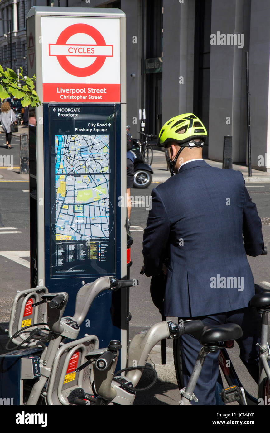 Geschäftsmann im Anzug, das Tragen eines Fahrradhelmes und Fahrrad fahren, Blick auf eine Radkarte von central London. Stockfoto