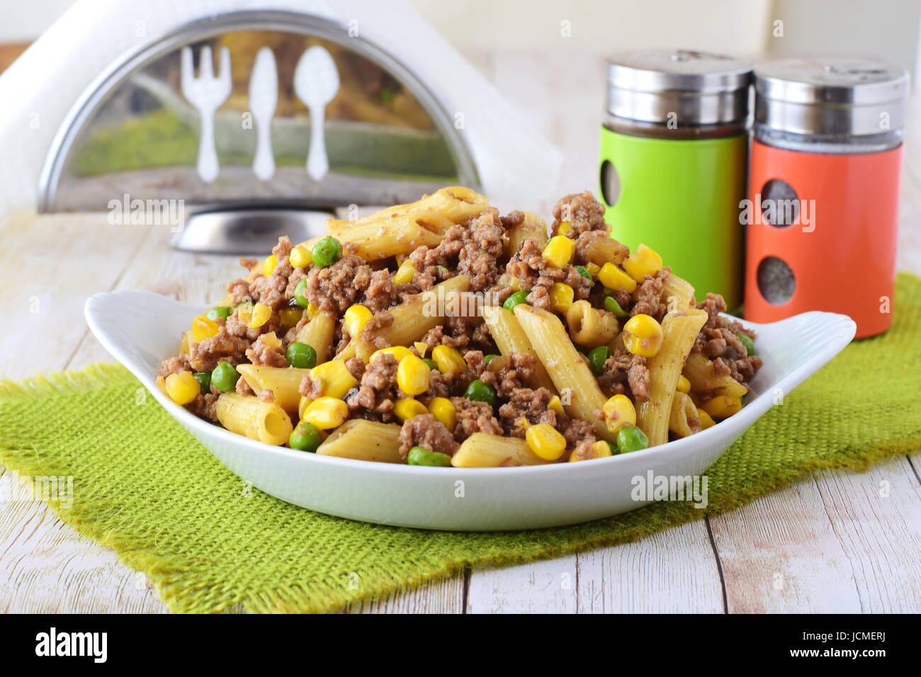 Pasta mit Hackfleisch, Erbsen und gelben Mais in einem weißen Teller. Hausmannskost. Gesunde Ernährung-Konzept Stockfoto