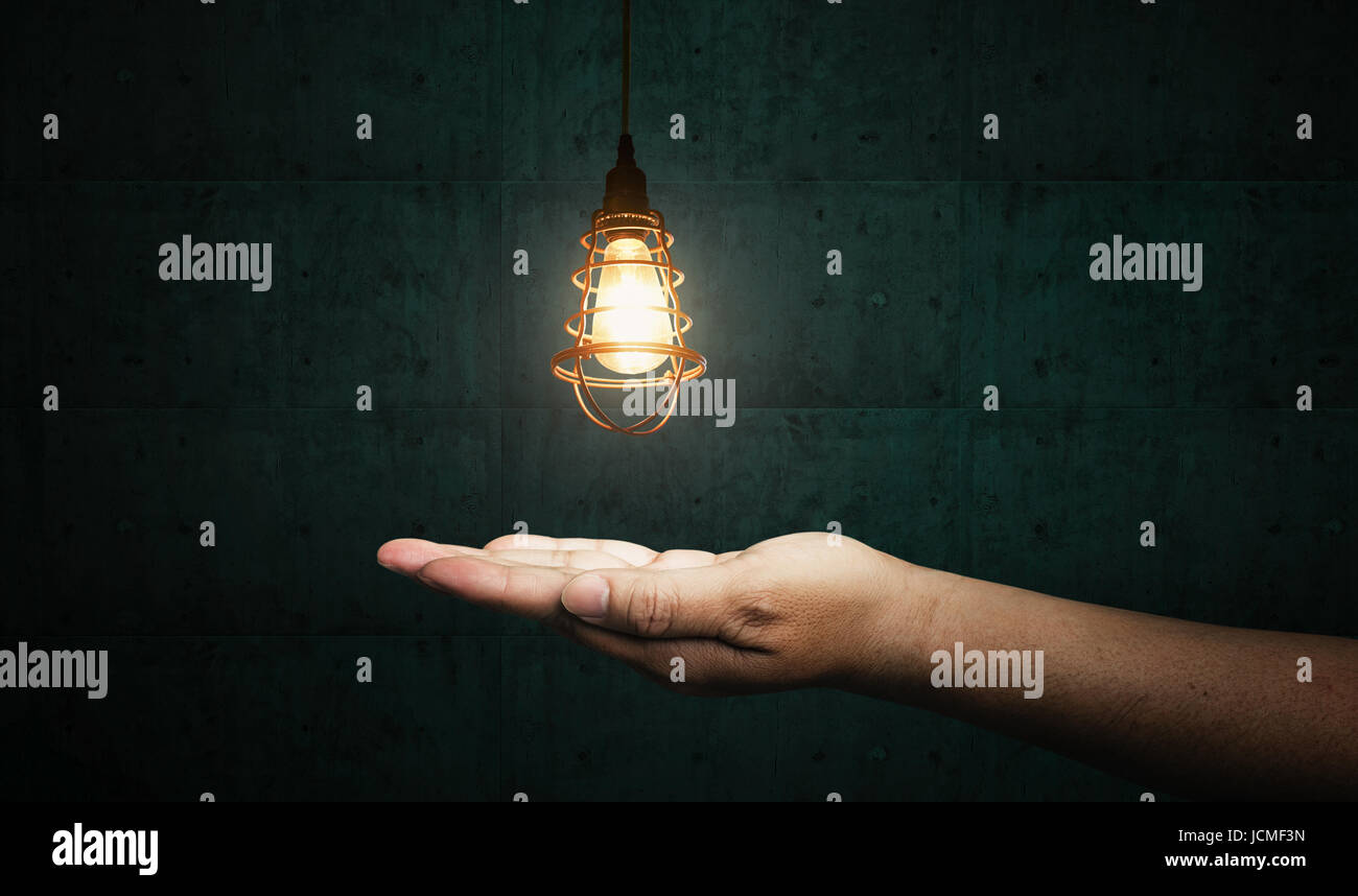 Geschäftsmann helle Idee halten in der hand mit blau Zement Hintergrund. Stockfoto