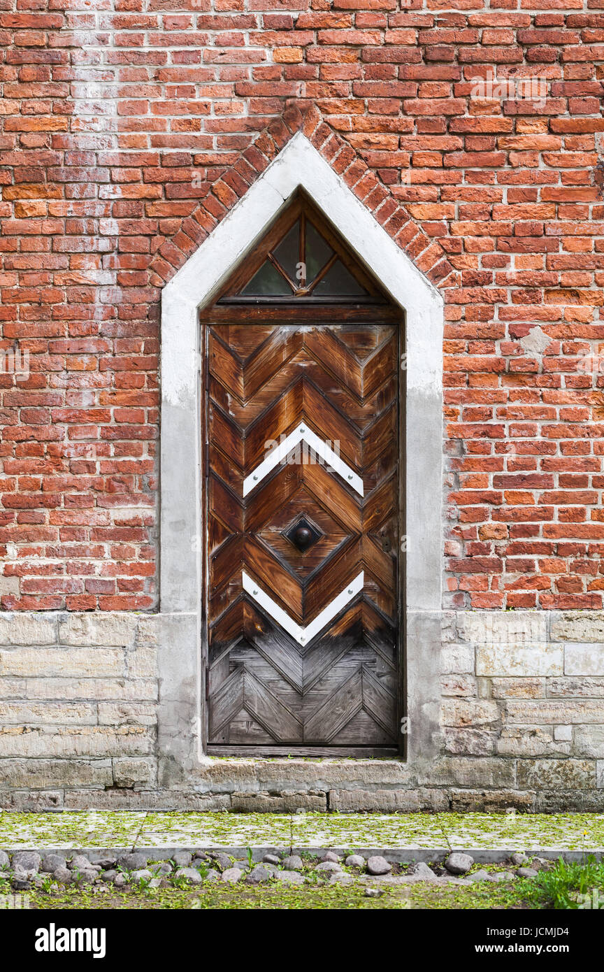 Dunkle Holztür in roten Backsteinmauer, neugotischen Architektur-Stil. Hintergrundtextur Stockfoto