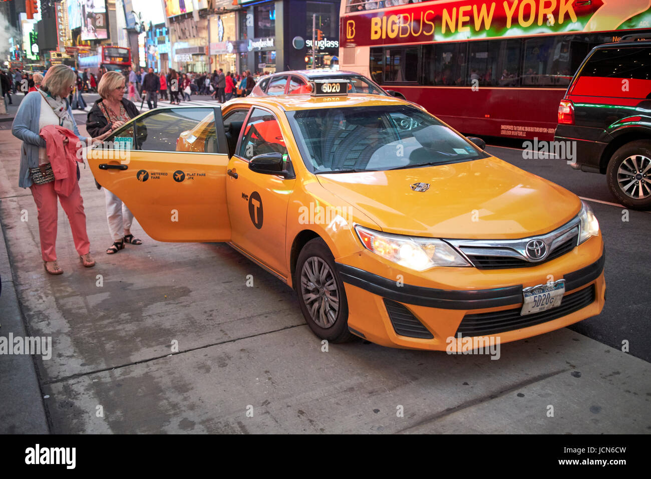 zwei Frauen, die immer in ein yellow Cab abends im Times Square New York City USA Stockfoto