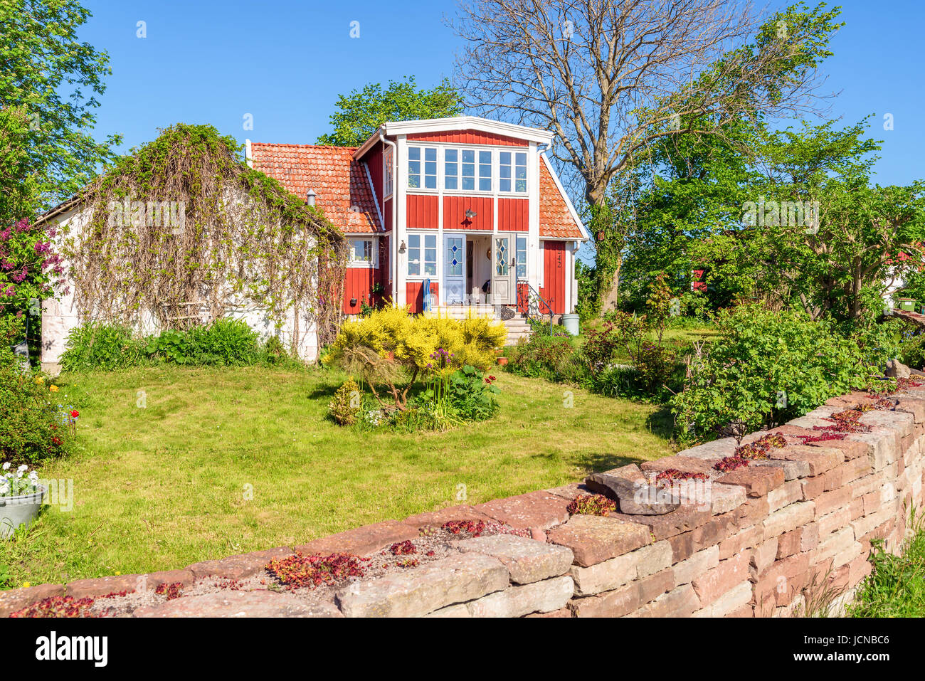 Ossby, Öland, Schweden - 28. Mai 2017: Umwelt-Dokumentarfilm. Schöne rote Haus und Garten in der kleinen Küstenstadt Dorf Ossby an einem sonnigen Tag. Stockfoto