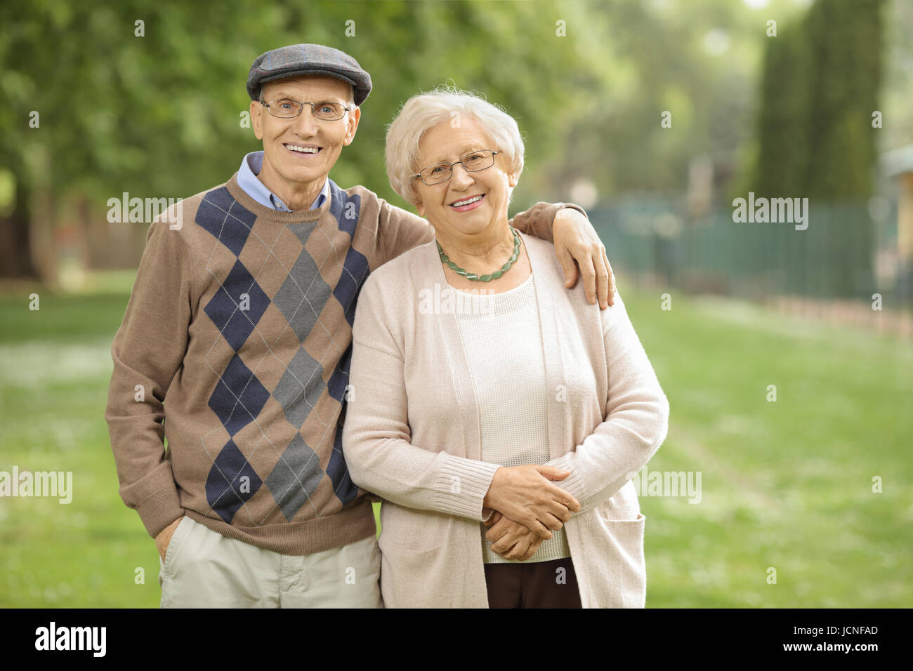 Älteres Paar im Park mit Blick auf die Kamera und lächelnd Stockfoto