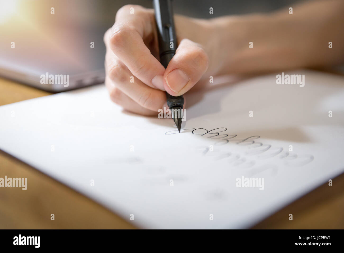 Fokus auf Hand mit schwarzen Füllfederhalter Praxis Kalligrafie auf weißem Papier mit weichem Licht von Ecke zu schließen. Stockfoto