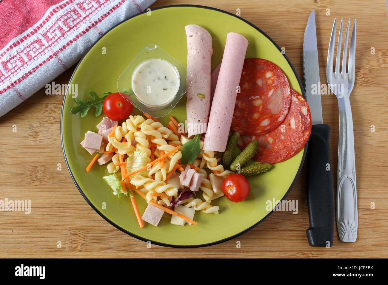 Ein Nudelsalat, Tomaten, Sauce und Wurst in einer Platte in Begleitung Stockfoto