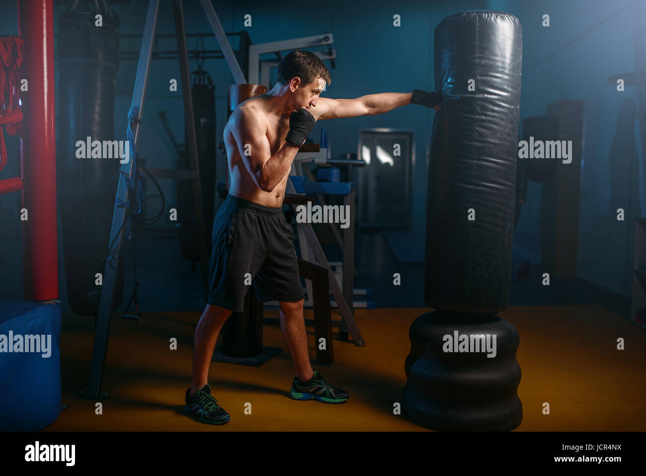 Mann in schwarz Boxbandagen Übungen mit Tasche im Fitness-Studio. Boxtraining, Herren sport Stockfoto