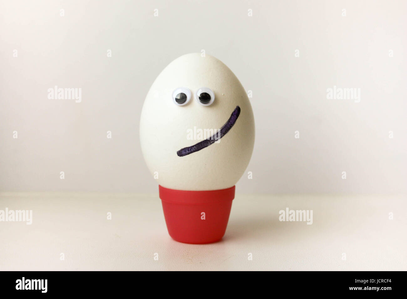 Ei-Lächeln. Konzept des Glücks. Ei mit lustigem bemalte Gesicht auf einem weißen Hintergrund. Foto für Ihr Design. Stockfoto