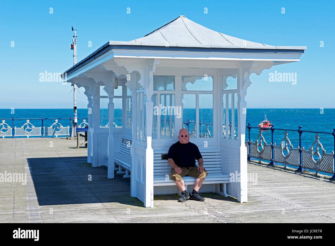 Mann, der im Tierheim sitzt und eine Alien-Maske trägt, Swanage, Dorset, England, Großbritannien Stockfoto